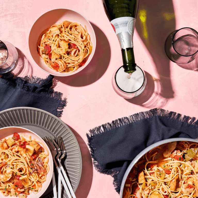 Bowls Of Seafood Pasta Paired With Sparkling Wine Being Poured