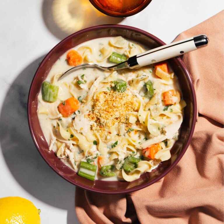 A bowl of Rotisserie Chicken Noodle Soup made with Ronzoni® Wide Egg Noodles, parmesan breadcrumbs, and a heavy-cream based broth.