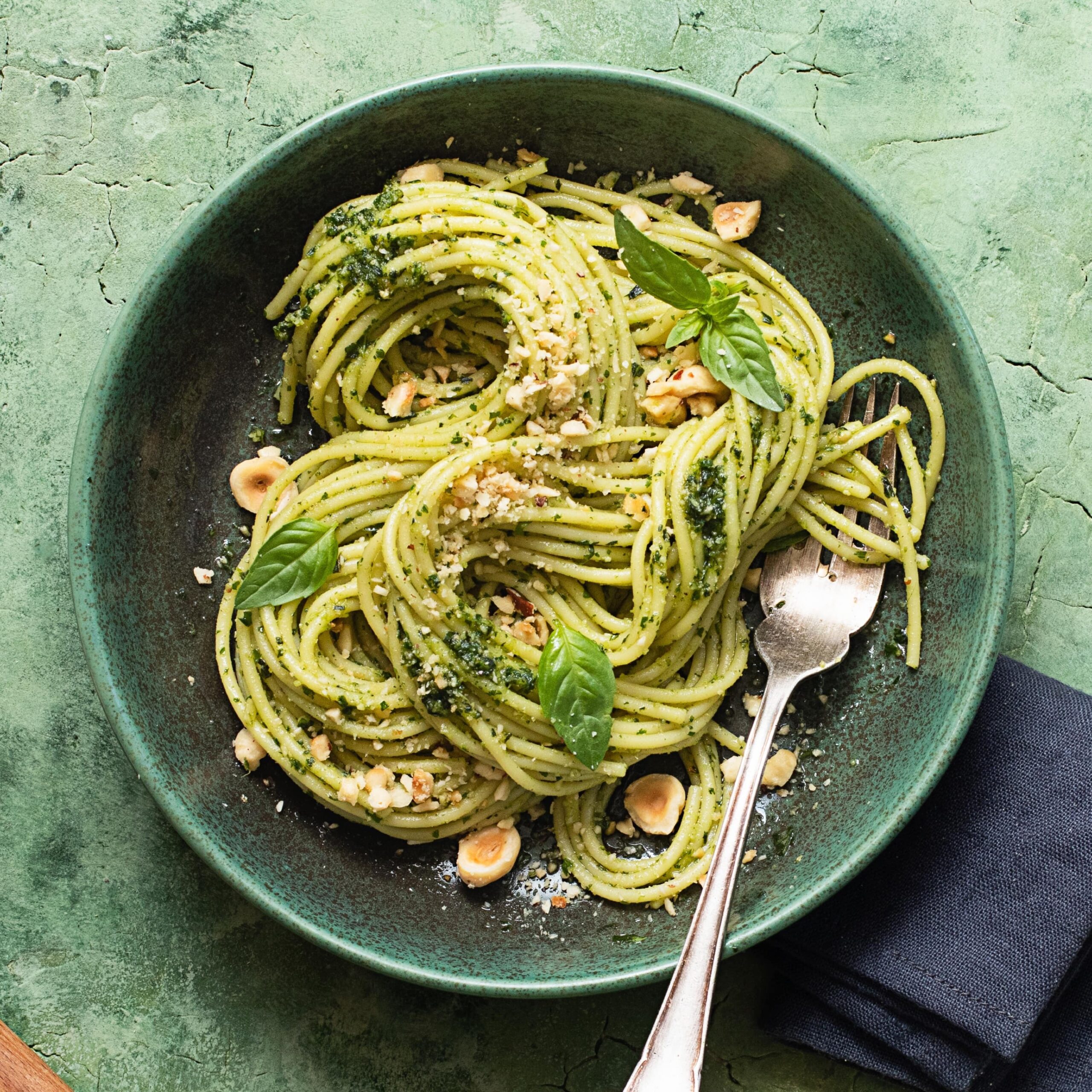 Thin pasta with hazelnut pesto, crushed hazelnuts, and herbs in serving dish