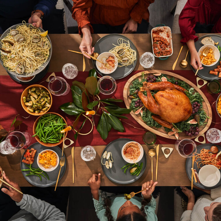 Holiday Tablescape Setting With Family Serving Pasta And Other Dishes