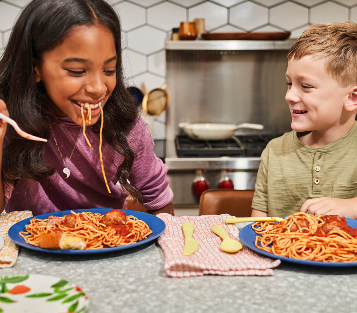 Joyful Kids Side By Side At Dinner Table Eating Spaghetti Pasta