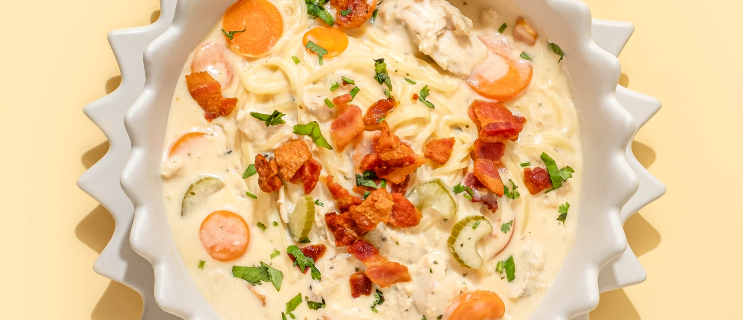 Long Pasta In Creamy Soup With Vegetables And Crispy Bacon