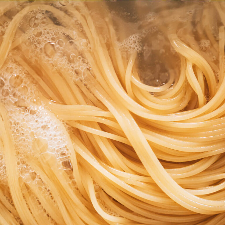 A long pasta shape in bubbling, boiling pasta water.