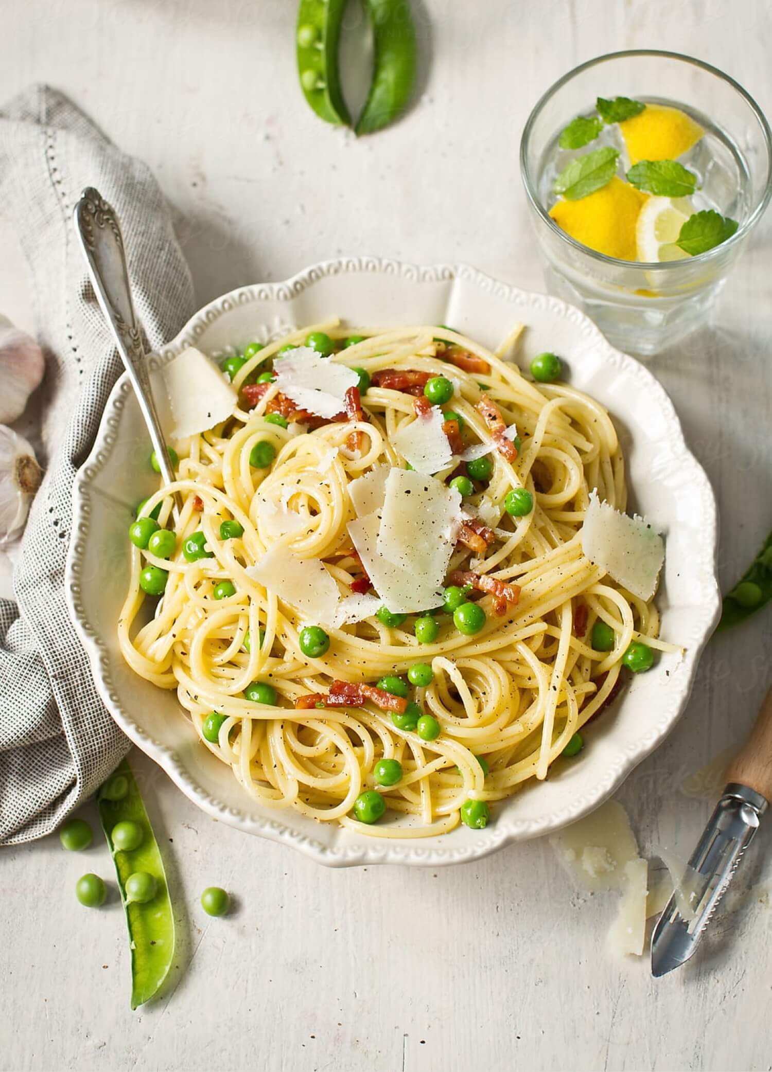 spaghetti carbonara with peas in serving bowl