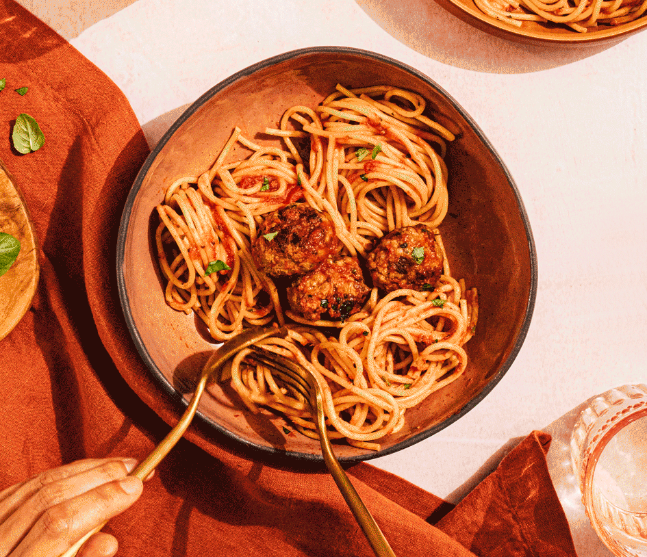 twirling spaghetti onto a fork above a bowl of spaghetti and and meatballs.