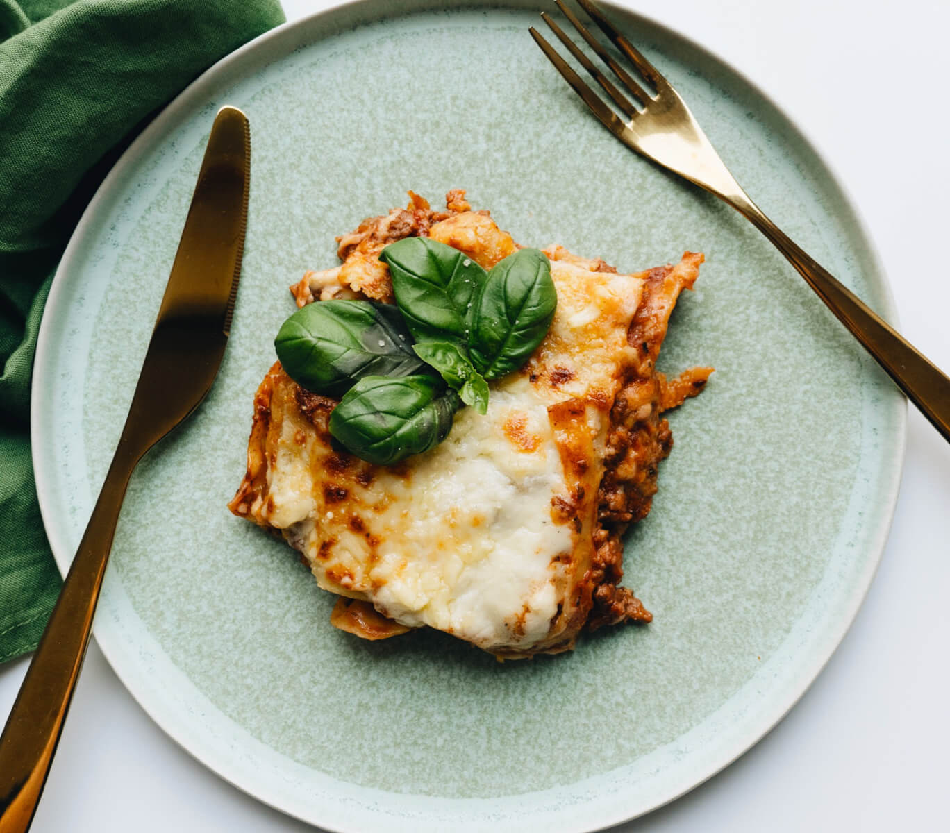 Ronzoni’s Easy Oven-Ready Lasagna on a plate with utensils and fresh basil.