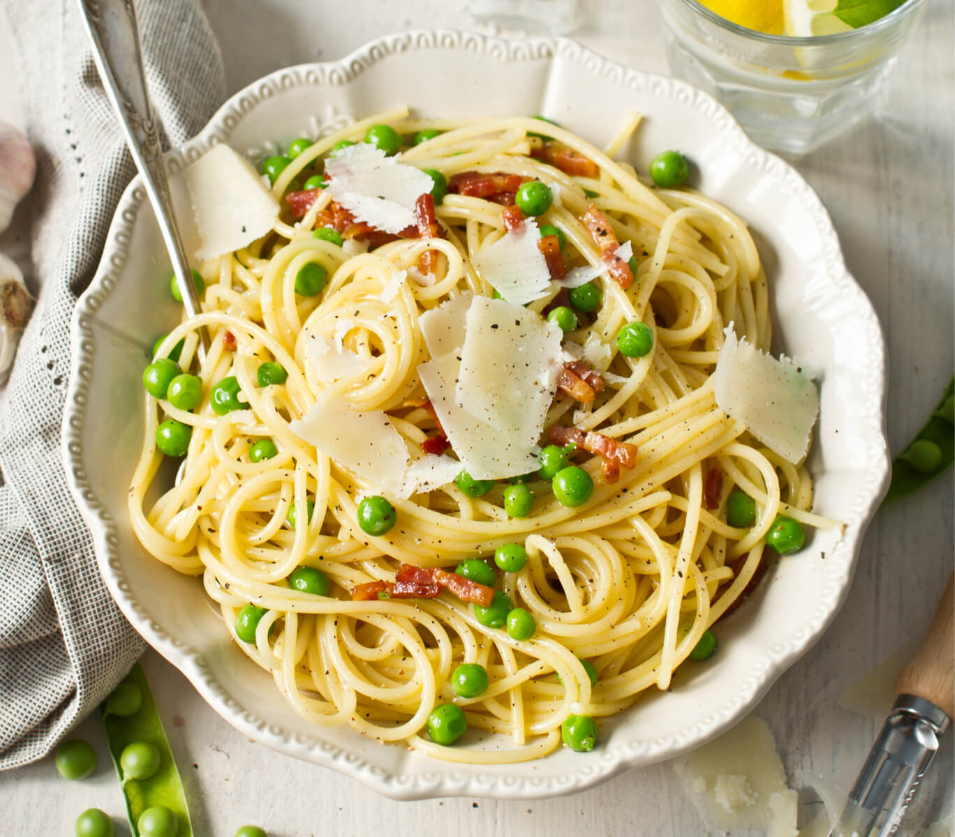 Ronzoni’s Spaghetti Carbonara with Peas in a bowl with utensils.